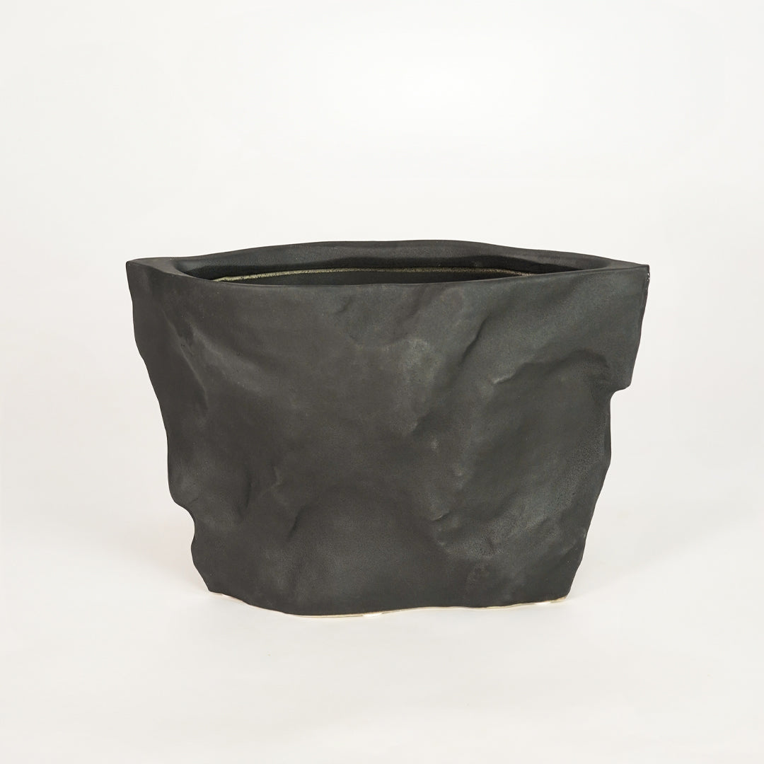 Closeup image of black ceramic decorative planter for modern shelf placement with textured matte finish styling.