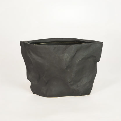 Closeup image of black ceramic decorative planter for modern shelf placement with textured matte finish styling.