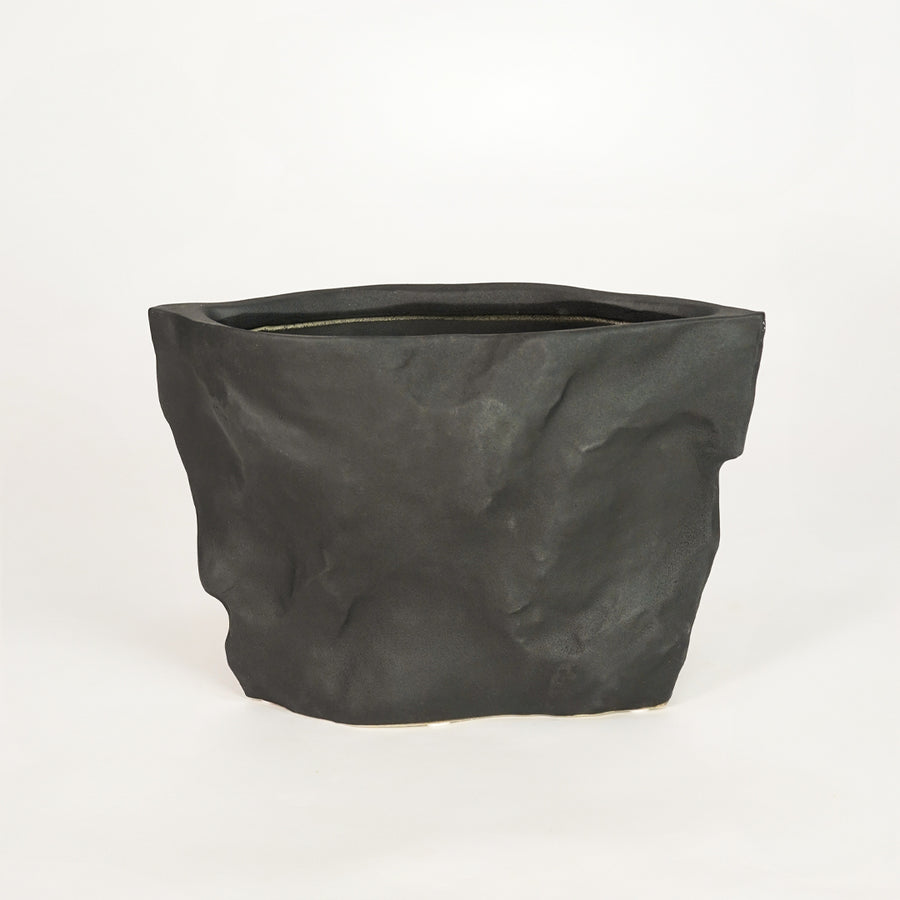 Closeup image of black ceramic decorative planter for modern shelf placement with textured matte finish styling.