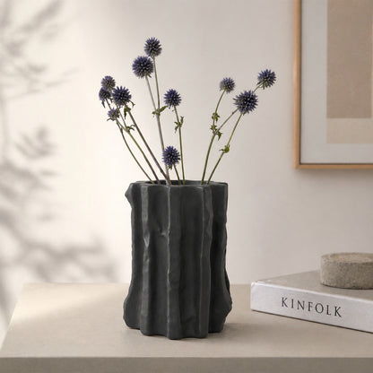 Black textured ceramic flower vase with dried blooms placed on table for modern home decor styling.