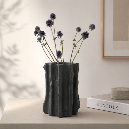 Black textured ceramic flower vase with dried blooms placed on table for modern home decor styling.