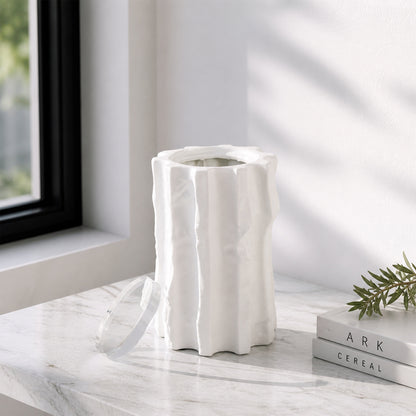 White textured ceramic vase placed on marble table for elegant modern home decor styling near window.