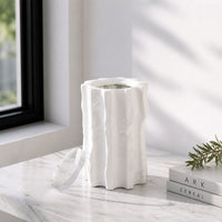 White textured ceramic vase placed on marble table for elegant modern home decor styling near window.