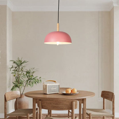 Pink metal pendant light above dining table adding soft Scandinavian charm and warm ambient lighting to interiors.