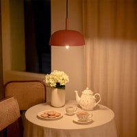Pink metal pendant light above tea table adding soft Scandinavian charm and warm ambient lighting to cozy interiors.