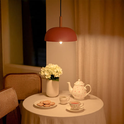 Pink metal pendant light above tea table adding soft Scandinavian charm and warm ambient lighting to cozy interiors.