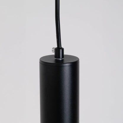 Closeup of slim black tubular pendant light showing smooth matte finish and refined cylindrical design.
