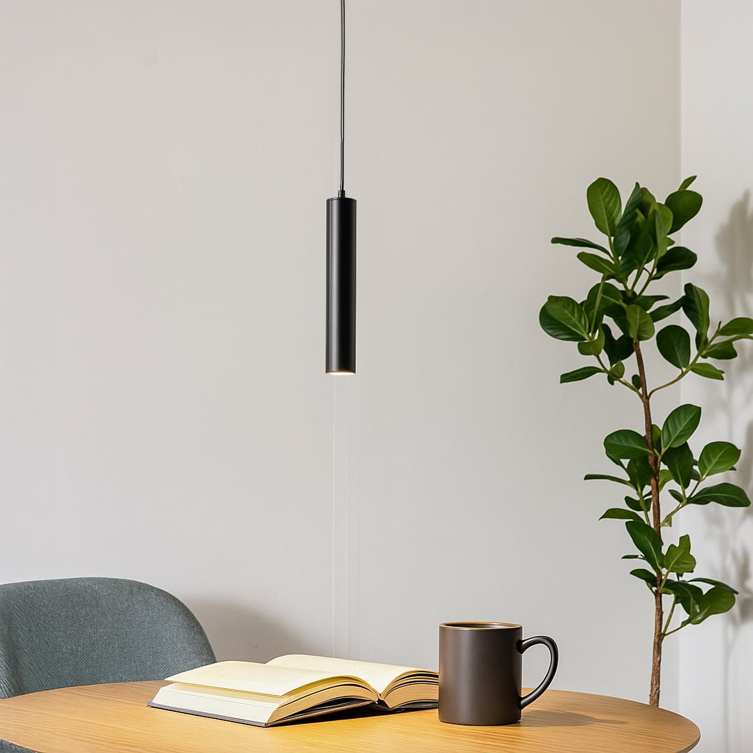 Modern black cylinder pendant light styled in a minimalist room creating focused downward lighting.