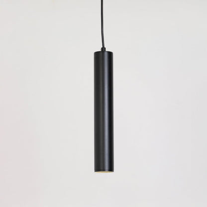 Black tubular pendant light glowing softly on a white background showing focused downward illumination.