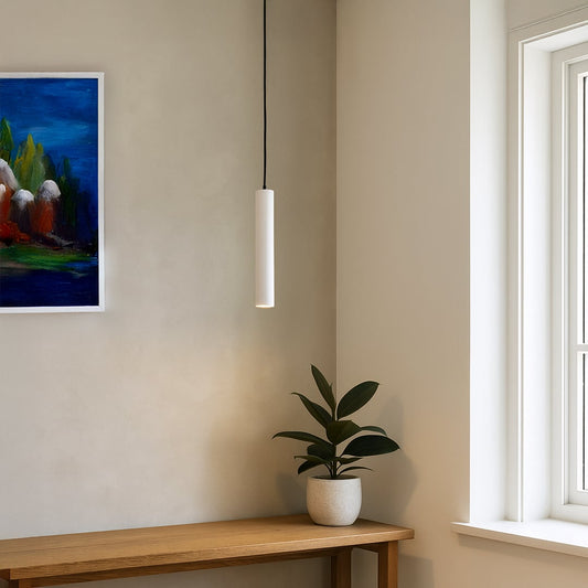 Slim white tubular pendant light adding clean modern lighting to a bright minimalist interior setting.