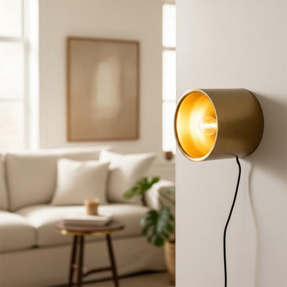 Chic gold cylindrical wall spotlight casting a warm yellow beam in a cozy modern living room lounge background scene.