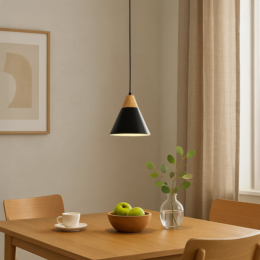 Black and wood pendant light hanging above a dining table creating warm ambient lighting for a modern minimalist dining room interior.