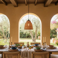 Natural rattan pendant light above dining table adding warm elegance to Mediterranean style interiors.