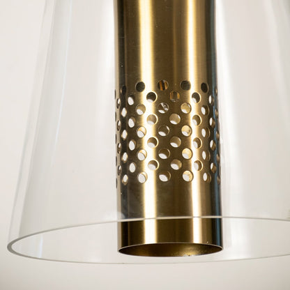 Closeup of brushed gold and clear glass pendant light showing perforated metal detail and elegant modern design for contemporary interiors.