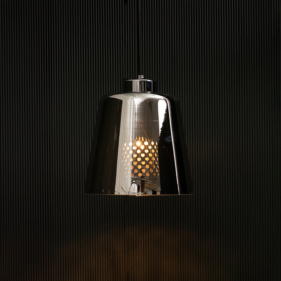 Smoked grey glass pendant light glowing on black background creating a dramatic modern lighting effect with a sleek reflective finish.
