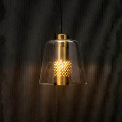 Glass pendant light with gold metal holder glowing on black background creating warm ambient lighting for modern interiors.