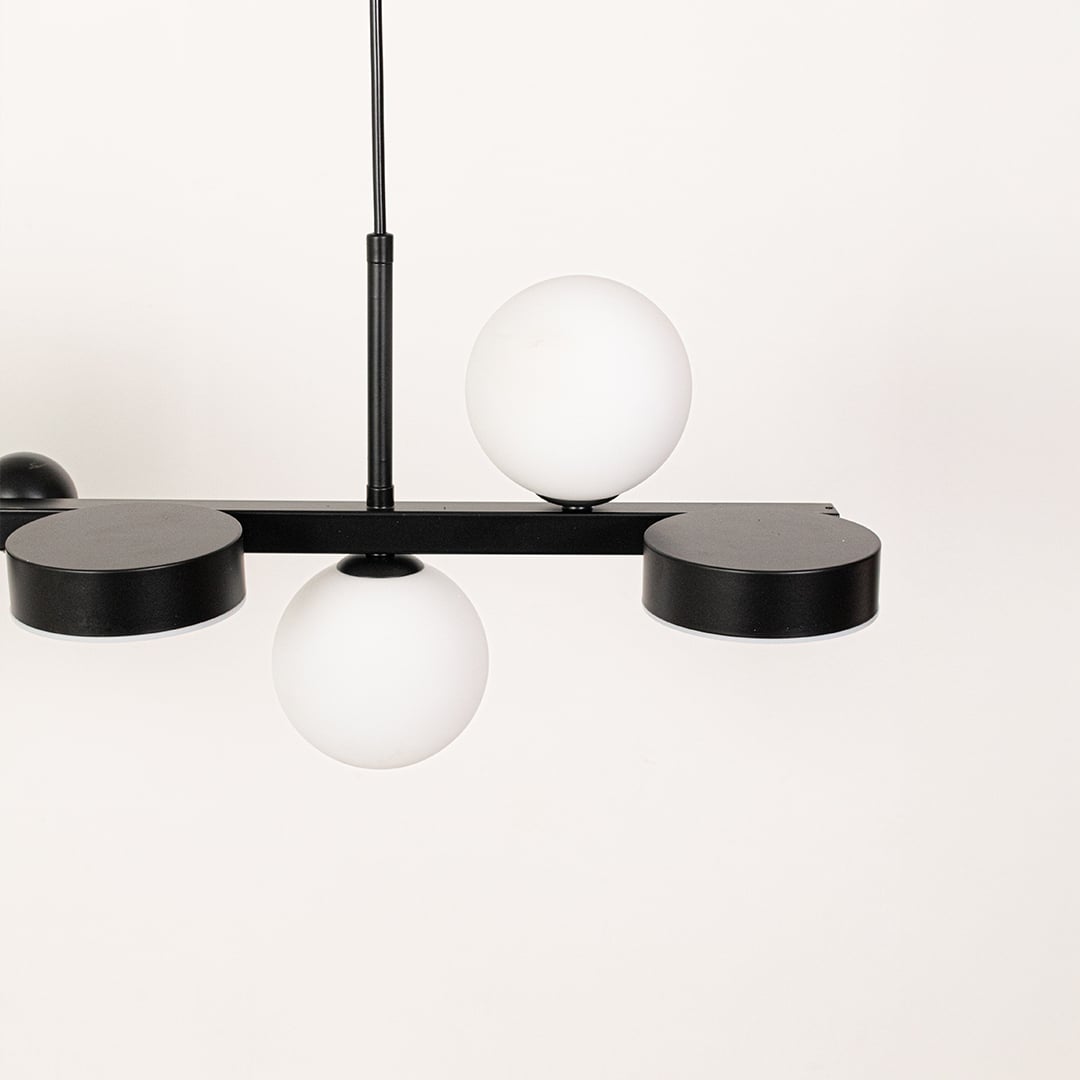Closeup of black metal chandelier highlighting the smooth white globes and sleek modern frame crafted for premium contemporary interior lighting.