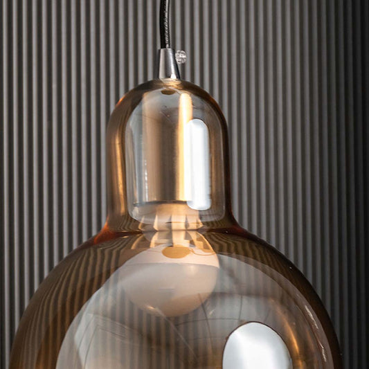 Closeup of amber glass and chrome metal pendant light showcasing reflective finish and craftsmanship.