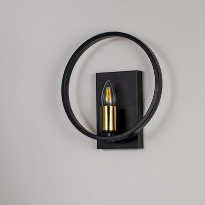 Modern wall light with matte black circular frame and gold bulb holder shown off on white background for stylish interiors.