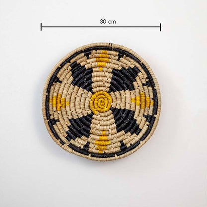 Handwoven seagrass round wall basket decor in natural beige black and mustard with floral pattern and size guide on white.