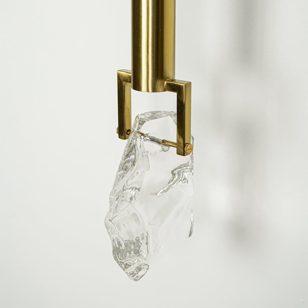 Closeup of gold metal wall light with crystal glass shade for luxury modern lighting decor styling ideas.