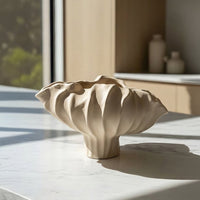 Beige ceramic decorative bowl with sculpted wave design placed on marble table for elegant home decor styling.