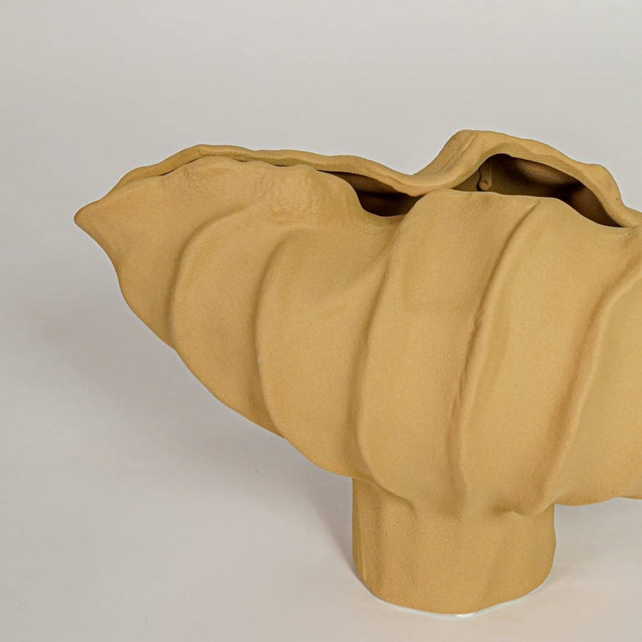 Detailed closeup of yellow ceramic sculpted bowl highlighting flowing textured form and contemporary design.