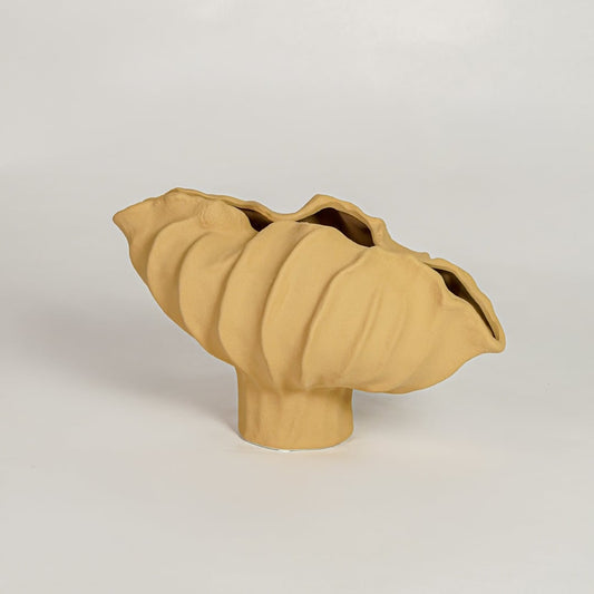 Yellow ceramic sculpted decorative bowl with flowing textured form isolated on white background for stylish decor placement.