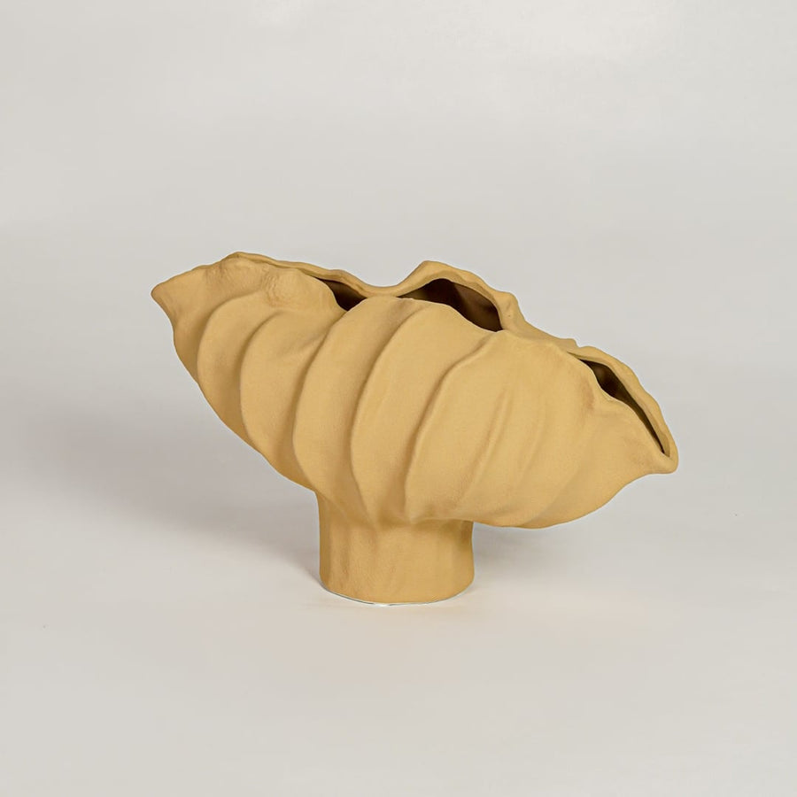 Yellow ceramic sculpted decorative bowl with flowing textured form isolated on white background for stylish decor placement.