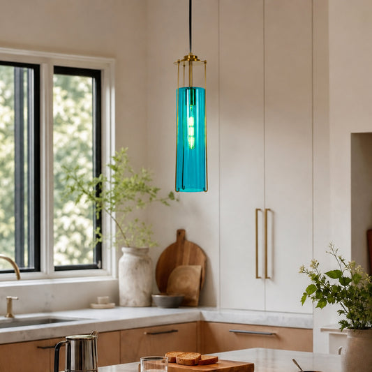 A modern cylindrical pendant light with a vibrant turquoise blue glass shade and gold-toned metal accents, hanging in a bright, contemporary kitchen.