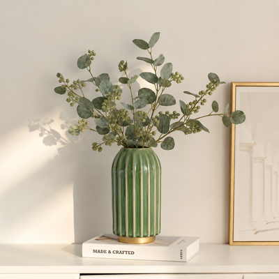 Lifestyle image of green gold ceramic vase for elegant living room decor styling with modern smooth decorative finish.