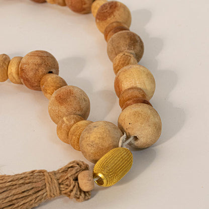 Detailed close-up of the wood bead garland highlighting its natural grain with a polished finish and jute tassel detail.