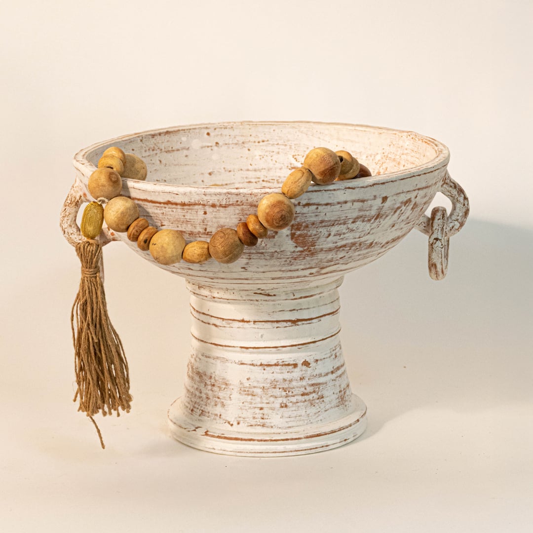Wood bead garland draped over a ceramic bowl creating an earthy vintage inspired home accent.