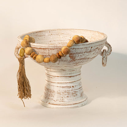 Wood bead garland draped over a ceramic bowl creating an earthy vintage inspired home accent.