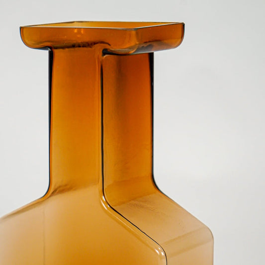 Close up view amber art glass vase showing sharp geometric edges smooth glossy finish decorative glass accent for shelf styling.