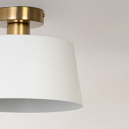 Closeup of white semi flush ceiling light with gold holder sleek dome design for modern bedroom dining room and hallway lighting.