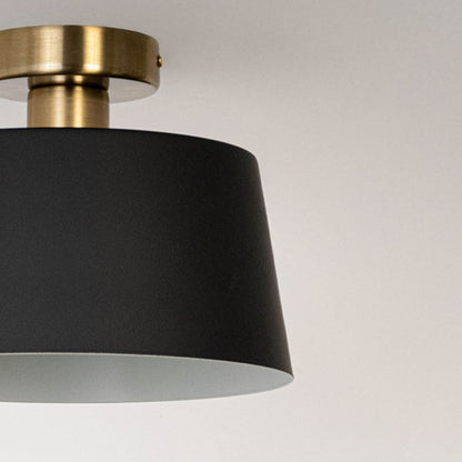 Closeup of black ceiling light with gold base and drum shade for modern ceiling lighting and elegant home interior decor.