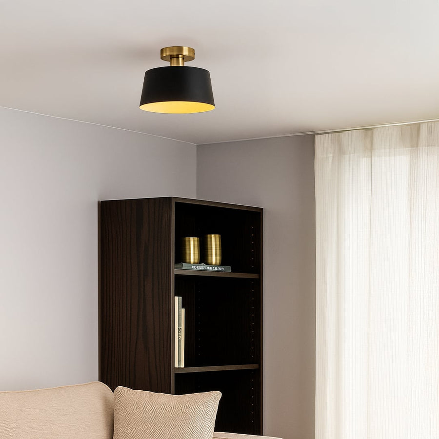 Modern black ceiling light with gold base and drum shade glowing warmly in living room for elegant home ceiling lighting.