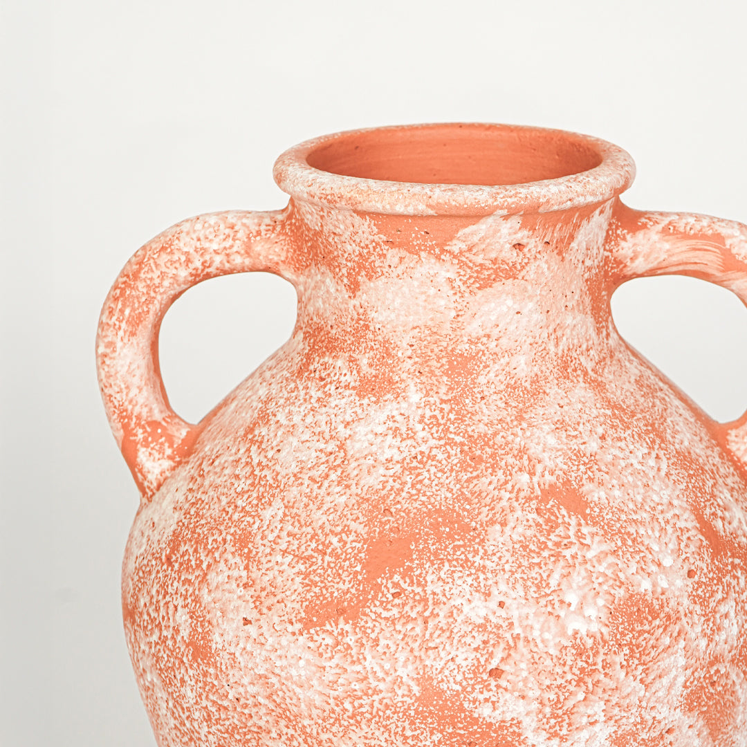 Closeup image of peach ceramic handle vase for modern shelf decor styling with artistic textured finish.