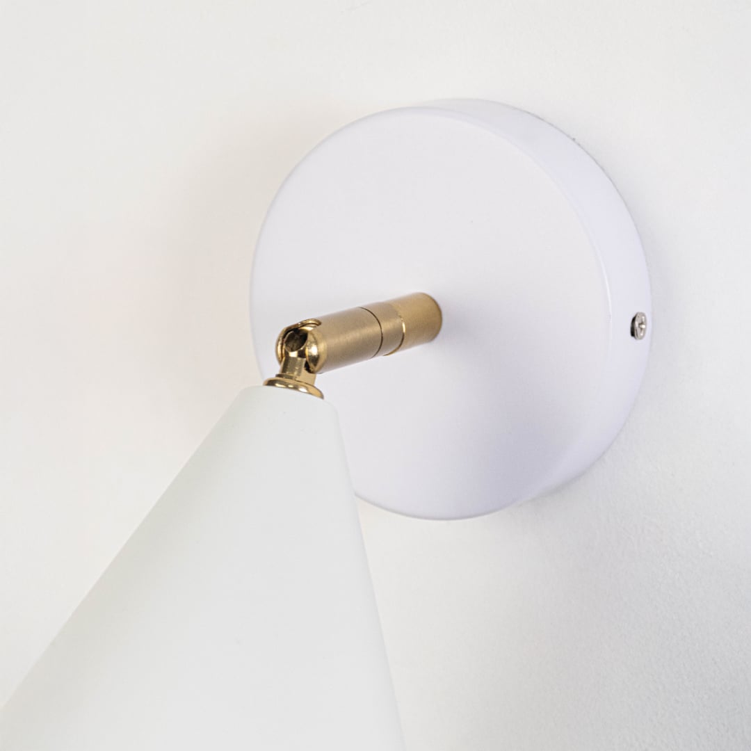 Closeup view of white metal wall sconce highlighting its conical shade smooth matte finish and warm lighting design suited for modern interior decor.