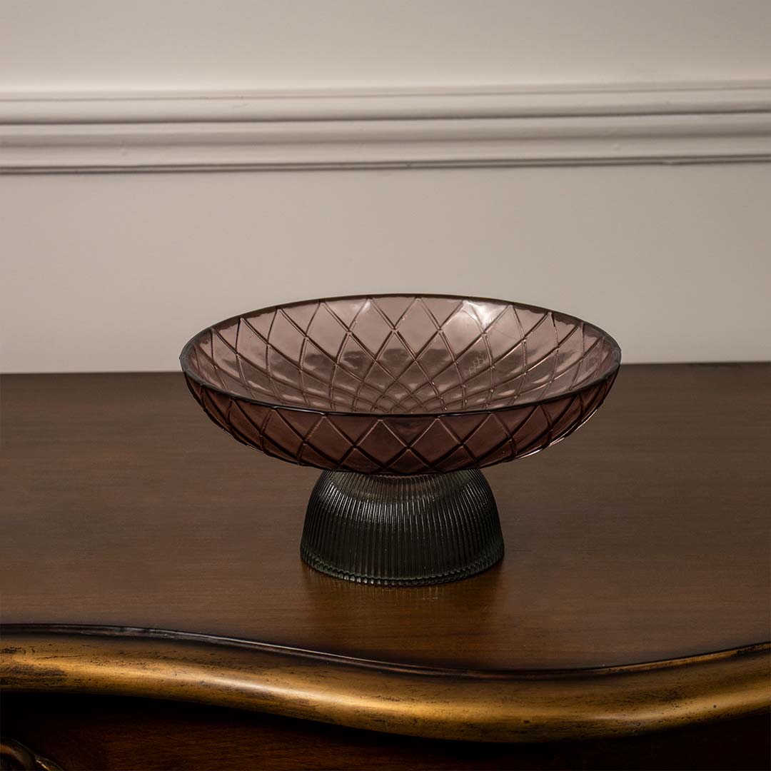 Modern smoky brown glass bowl with criss-cross embossed pattern and dark ribbed pedestal base on a plain white backdrop.