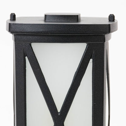 Closeup of black outdoor wall lantern showing textured metal frame frosted glass panel and sturdy weather resistant construction.
