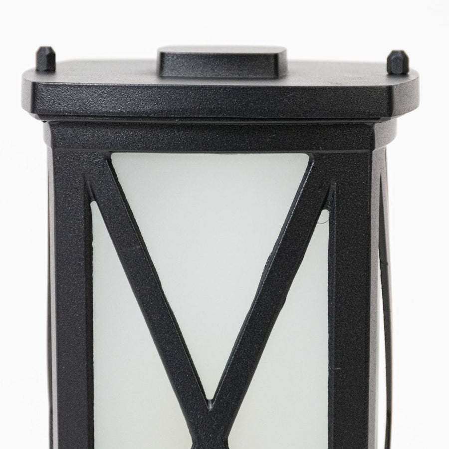 Closeup of black outdoor wall lantern showing textured metal frame frosted glass panel and sturdy weather resistant construction.