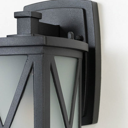 Black metal outdoor wall lantern closeup image showing textured matte frame and frosted glass with X overlay for decor.