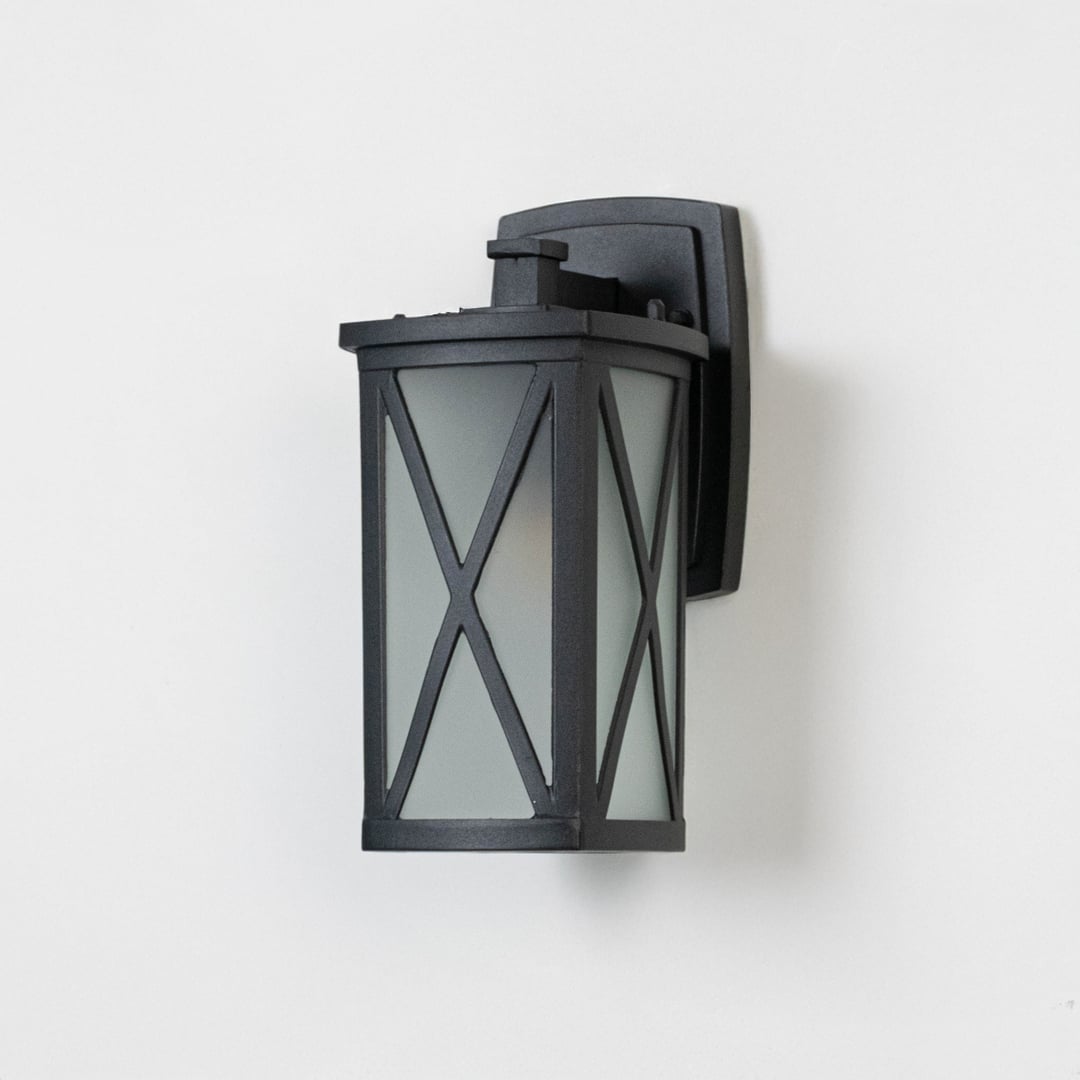 Black metal outdoor wall lantern on white background featuring frosted glass and an X frame overlay for modern porch decor.