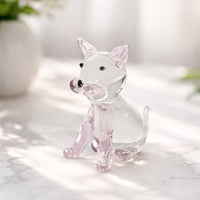 Clear glass dog figurine with soft pink accents placed on marble surface against bright background creating elegant minimal home decor aesthetic.