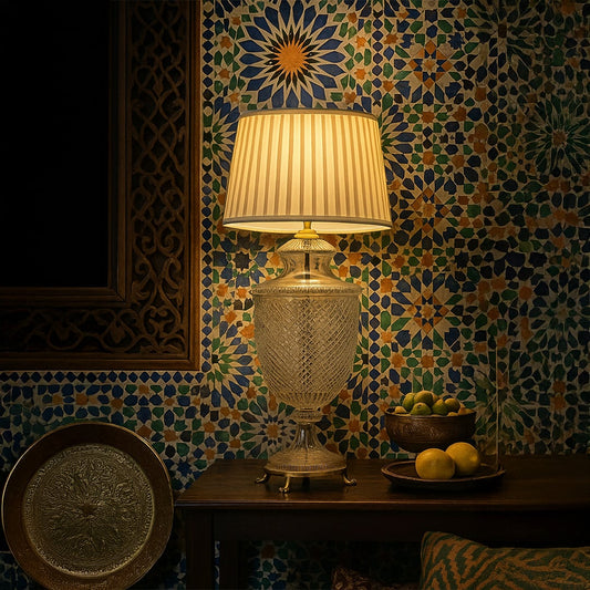 Clear etched glass table lamp with pleated fabric shade creating warm ambient lighting in a luxurious traditional interior.
