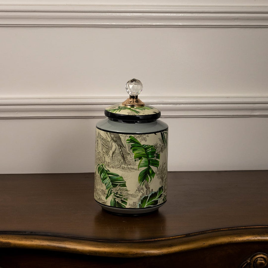 Tropical bird jar with crystal lid and hand-painted tropical bird and leaf design on white background.