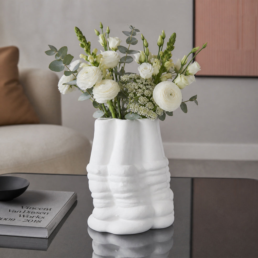 White textured ceramic flower vase with fresh blooms placed on modern coffee table in elegant living room.