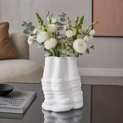 White textured ceramic flower vase with fresh blooms placed on modern coffee table in elegant living room.